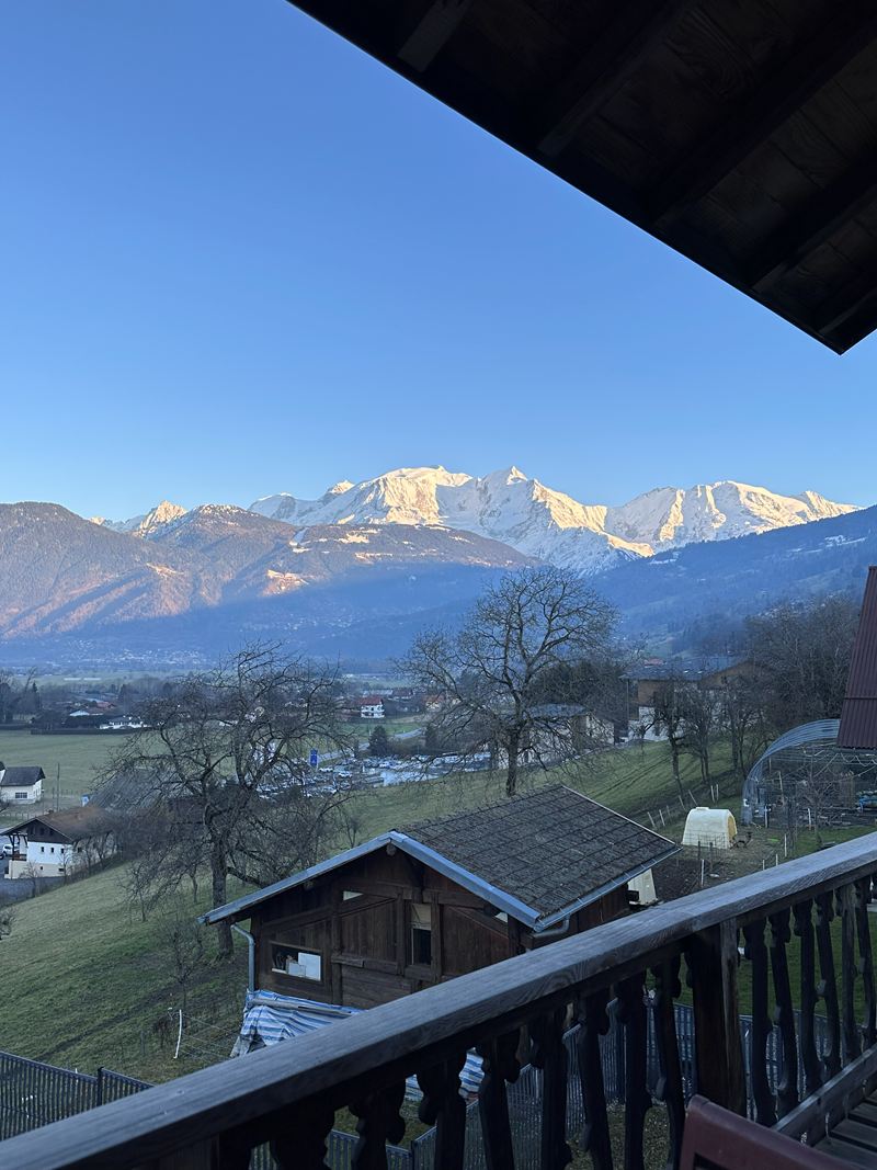 Snow-capped mountains seen from a wooden chalet balcony
