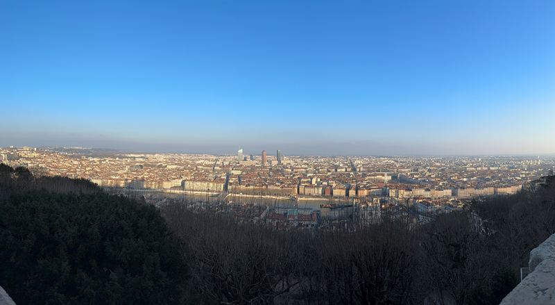 Panorama of a city spread out below a wooded hilltop
