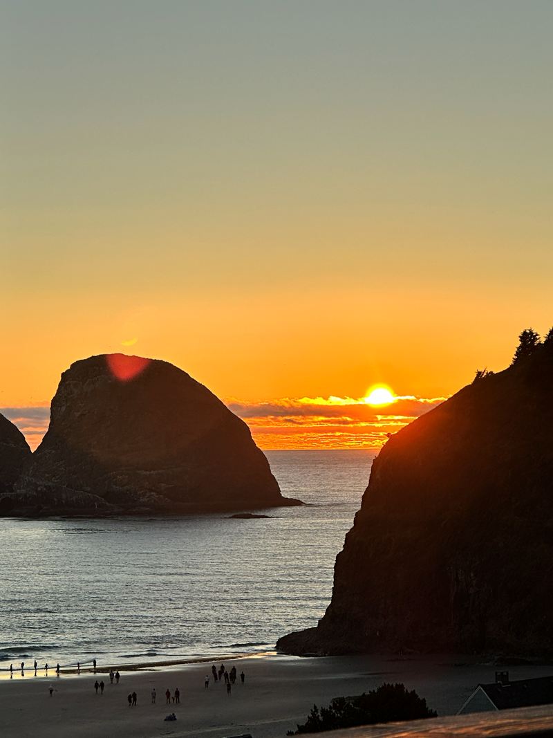 The sun setting between rocky sea stacks