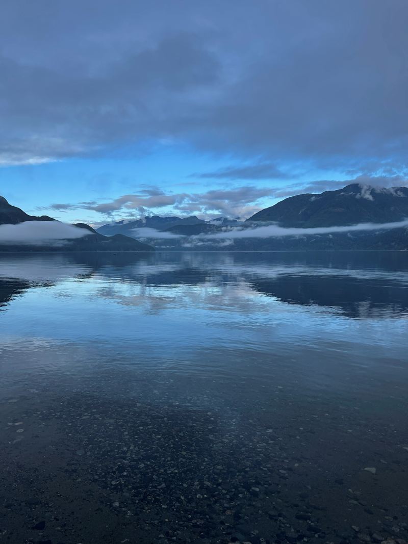 Low clouds and mountains reflected in calm water