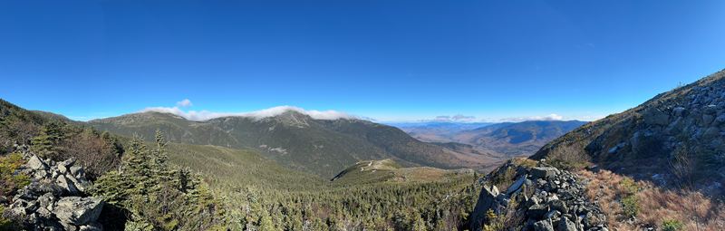 Panorama over forested mountains under a bright blue sky