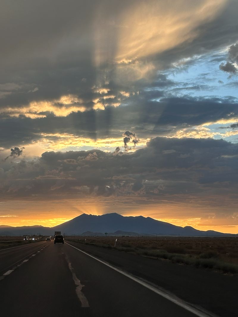 Sunbeams over a mountain and an open road at dusk