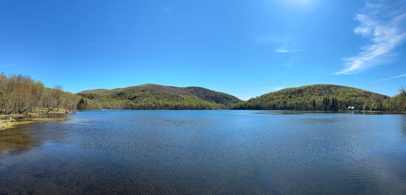 A calm lake surrounded by green, rolling hills